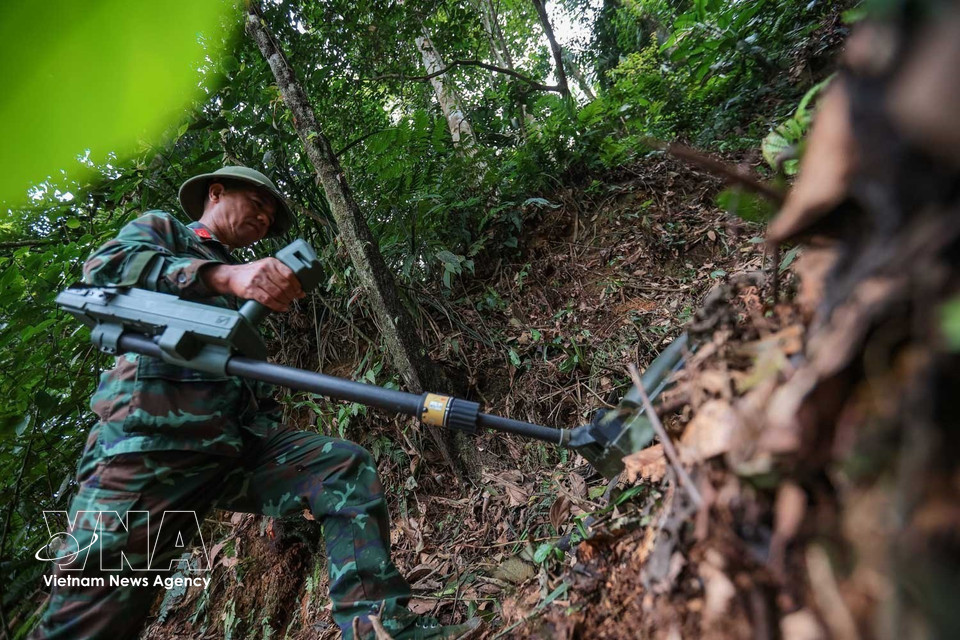 Sử dụng máy dò để tìm kiếm, xử lý bom mìn, vật liệu nổ còn sót lại tại khu vực tìm kiếm, quy tập hài cốt liệt sĩ. (Ảnh: TTXVN)